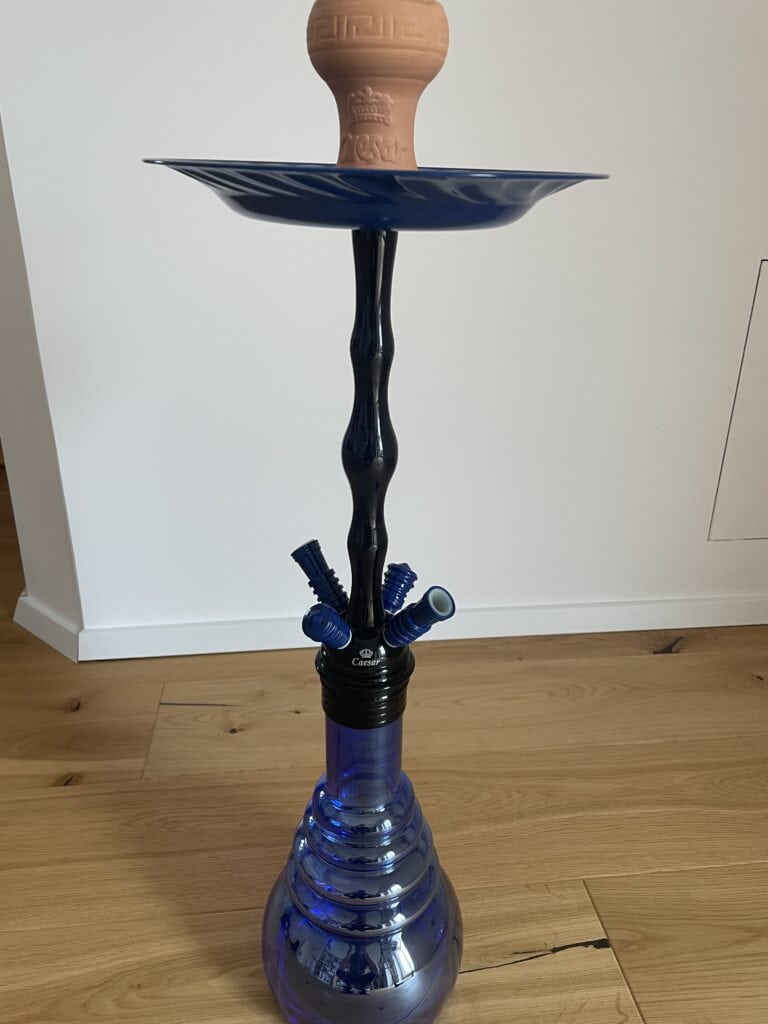 Rauchende Wasserpfeife mit blauer Glasbasis, Keramikschale und Metallrohr.