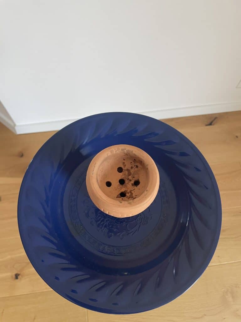Rauchfackel mit mehreren Löchern, auf blauer Platte präsentiert.