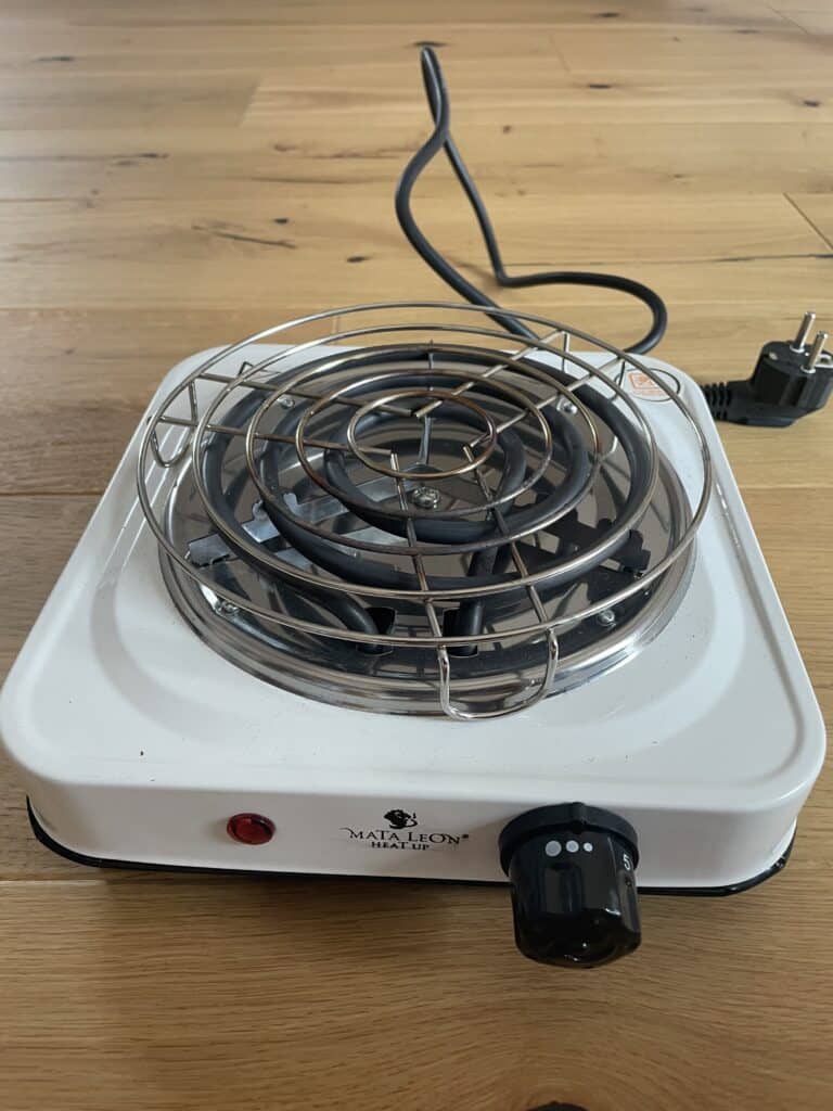 Kleine elektrische Herdplatte mit Heizspirale, ideal für Camping oder kleine Küchen.