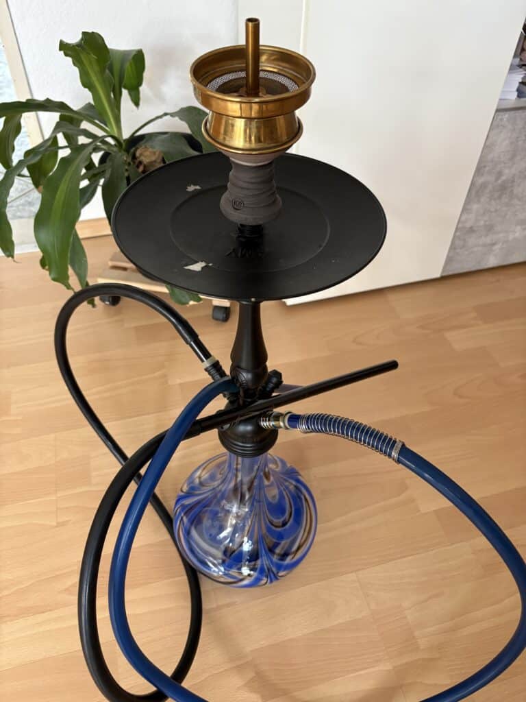 Rauchsäule mit Wasserpfeife, Schlauch und Tabakkopf für Shisha-Genuss. Perfekt für gemütliche Abende.