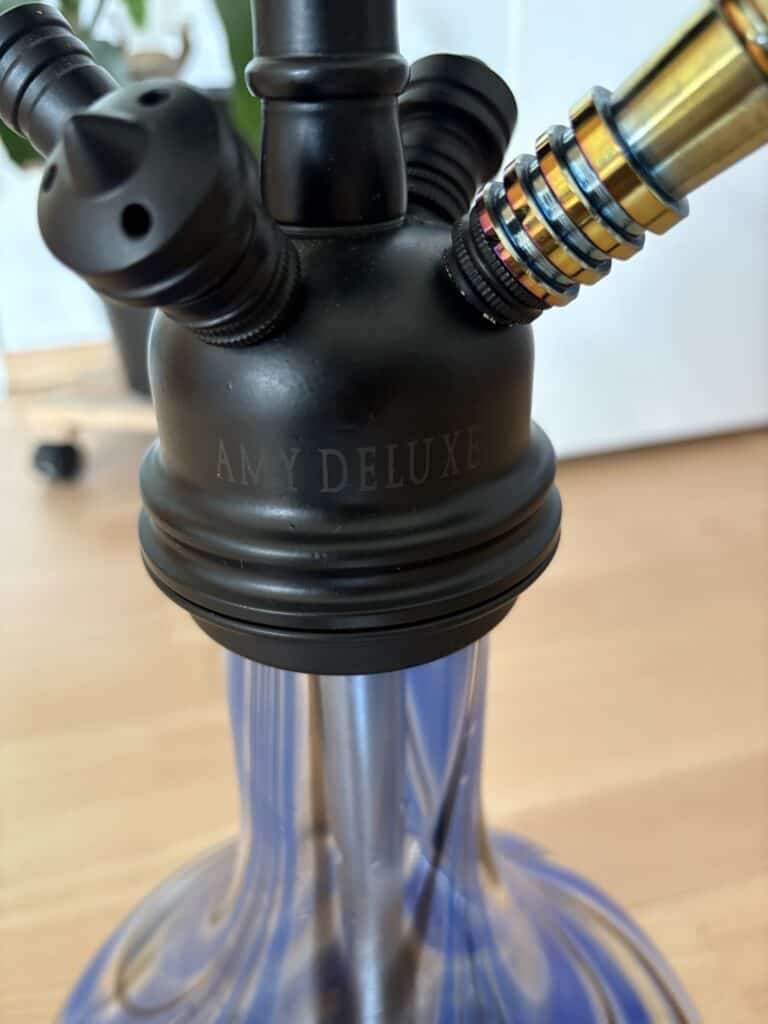 Shisha-Kopf mit goldener Rauchsäule und Glasbasis, ideal für Wasserpfeifenliebhaber.