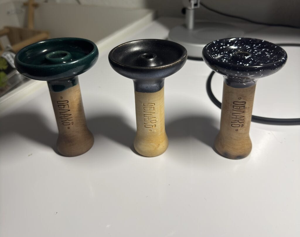 Drei verschiedene Shisha-Köpfe in Grün, Schwarz und mit Sternenmuster, ideal für Wasserpfeifen.