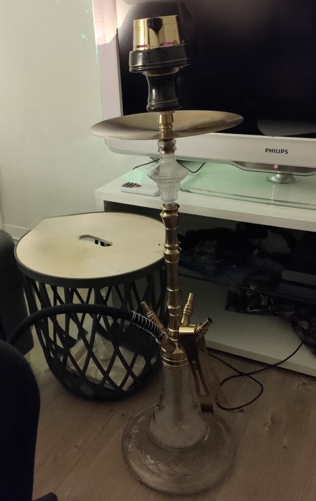 Rauchende Shisha mit Glasbowl, Metallrohr und Kopf, ideal für Wasserpfeifen-Liebhaber.