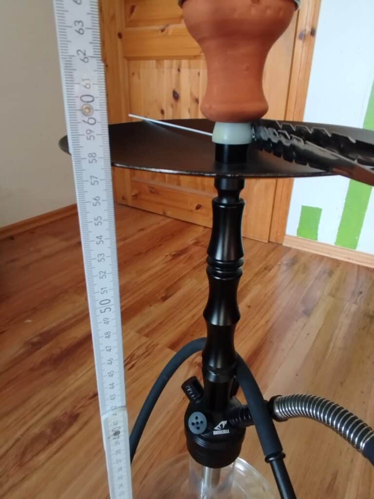 Rauchsäule mit Wasserpfeife auf Holztisch, Messung zeigt Höhe, Shisha im Innenraum.