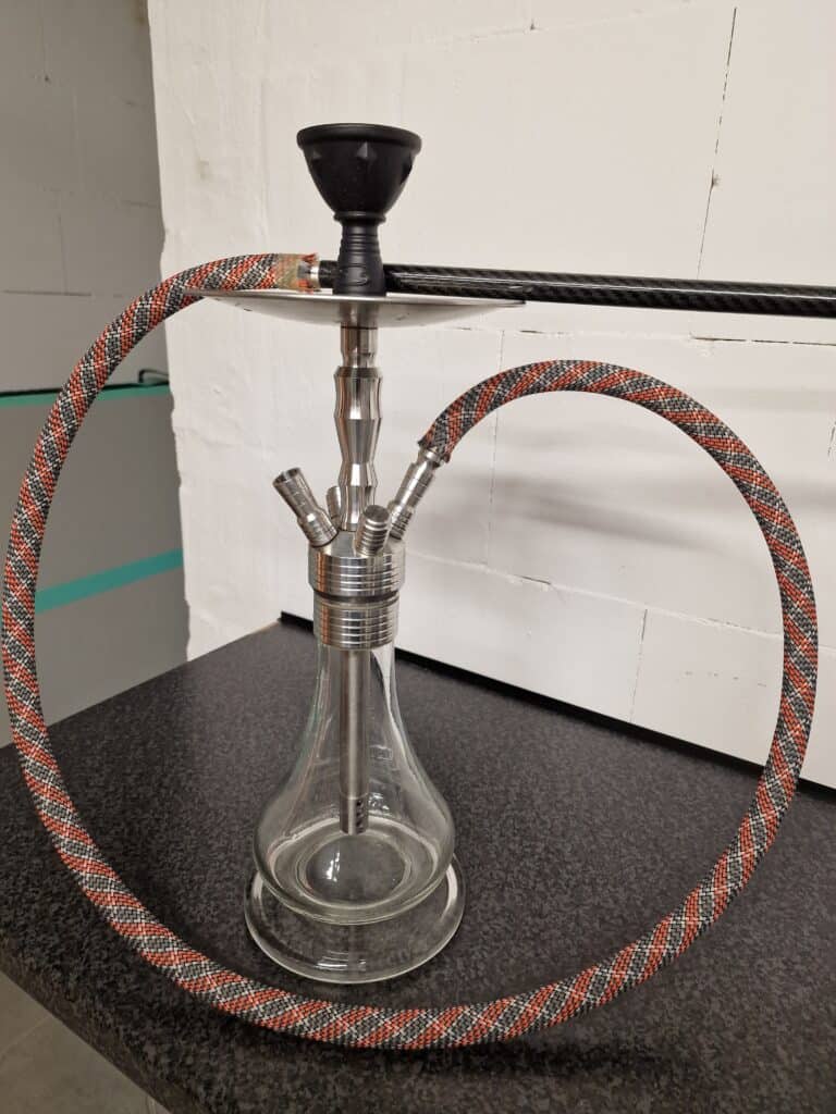 Shisha mit Glasgefäß, Metallrohr und bunter Schlauch für Raucher.