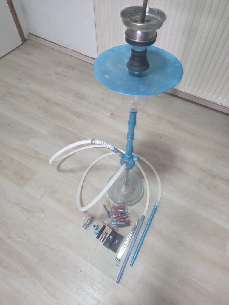Shisha mit Zubehör und Kohle auf Boden.