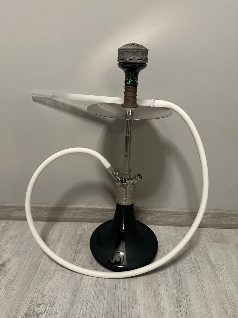 Moderne Shisha mit Zubehör auf Boden, weißer Hintergrund.