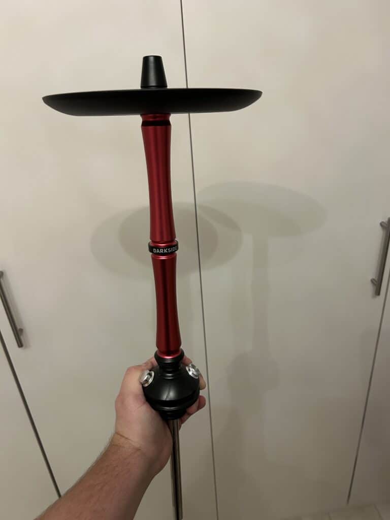 Hand hält eine Hookah mit schwarzer Glas-Bowl und rotem Metall-Stem.