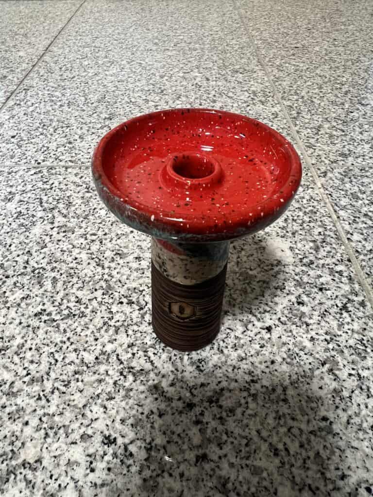 Shisha-Kopf in Rot und Schwarz, ideal für Wasserpfeifen, auf Fliesenboden präsentiert.