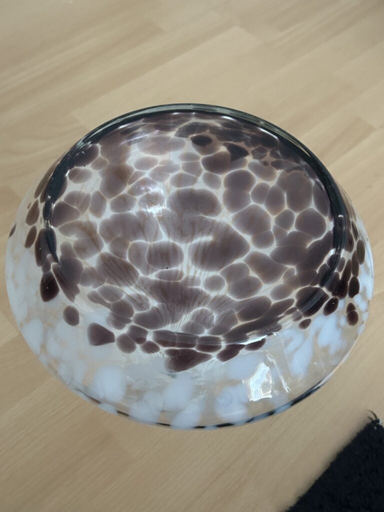 Glas mit Wasser und Lichtreflexen auf Holztisch.