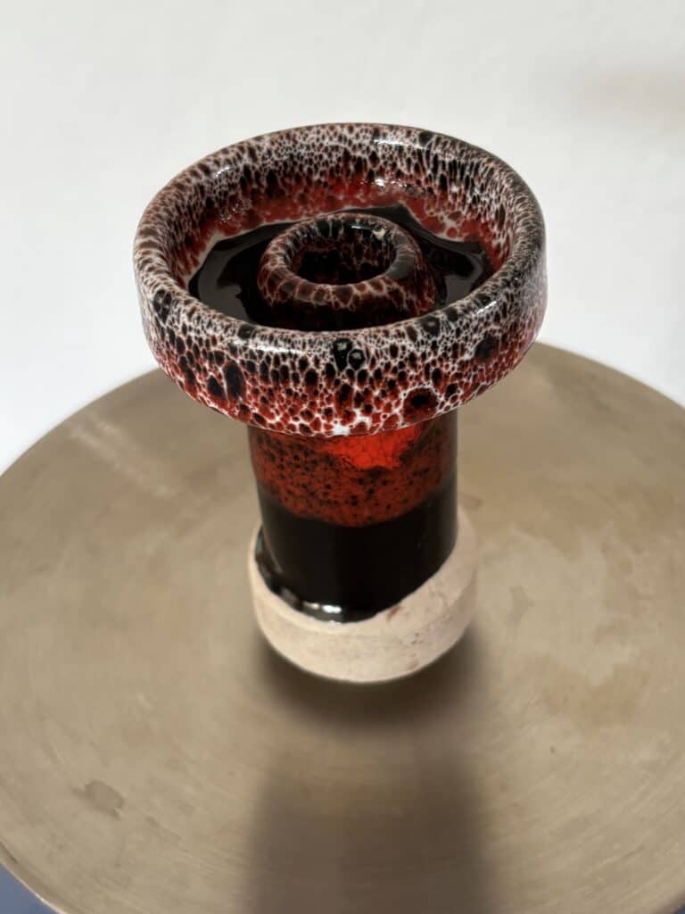 Dekorative Glasvase mit rotem, rauchigem Glasdesign auf Holzoberfläche.