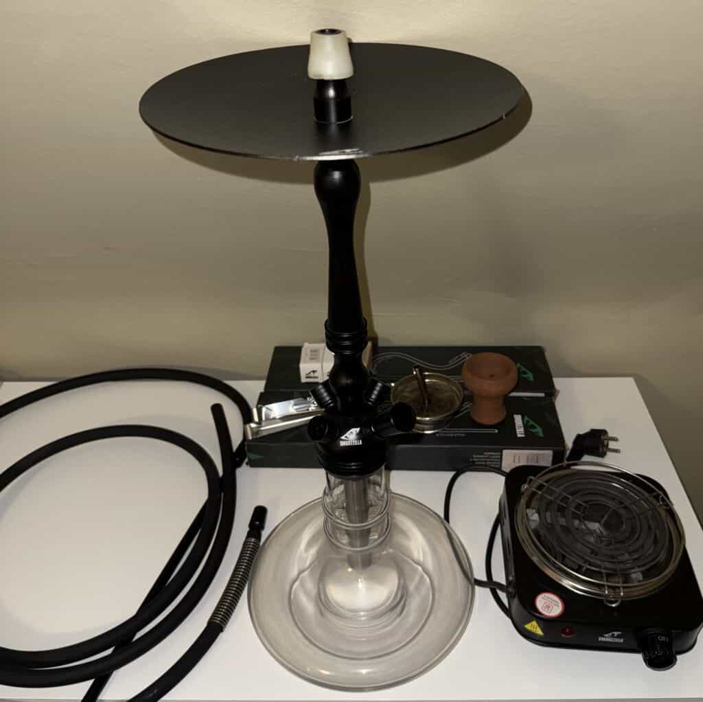 Shisha mit Zubehör, Kohle und Heizgerät auf Tisch.