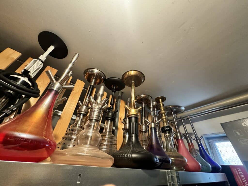 Verschiedene Shisha-Köpfe und Rauchpfeifen auf einem Regal.
