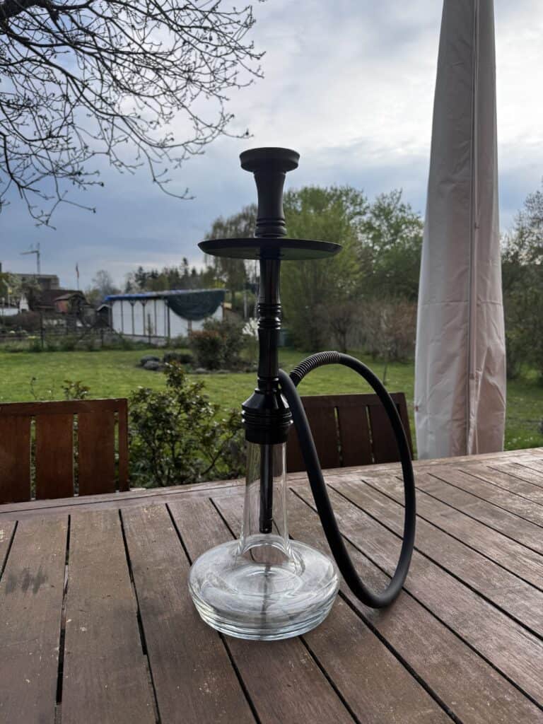 Wasserpfeife (Shisha) mit Glasbasis und schwarzem Schlauch im Freien.