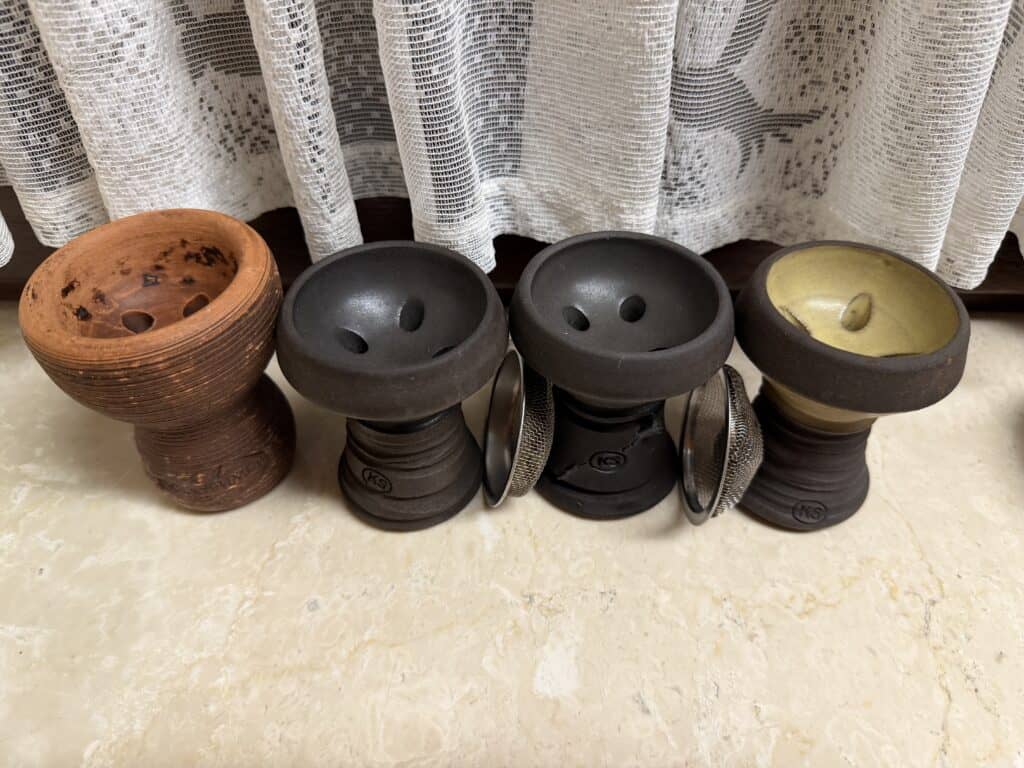Verschiedene Feuerkörbe und Shisha-Teile in Schwarz, Braun und Gold.