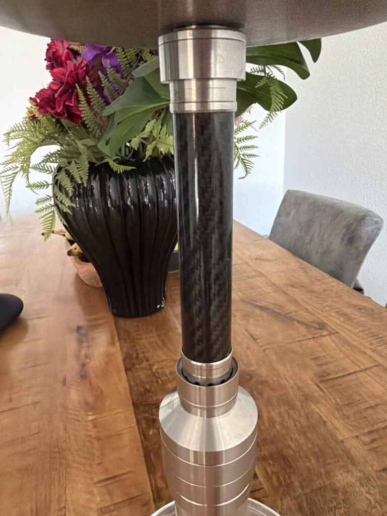 Halterung für Shisha, Edelstahloptik, auf Holztisch mit Blumen im Hintergrund.