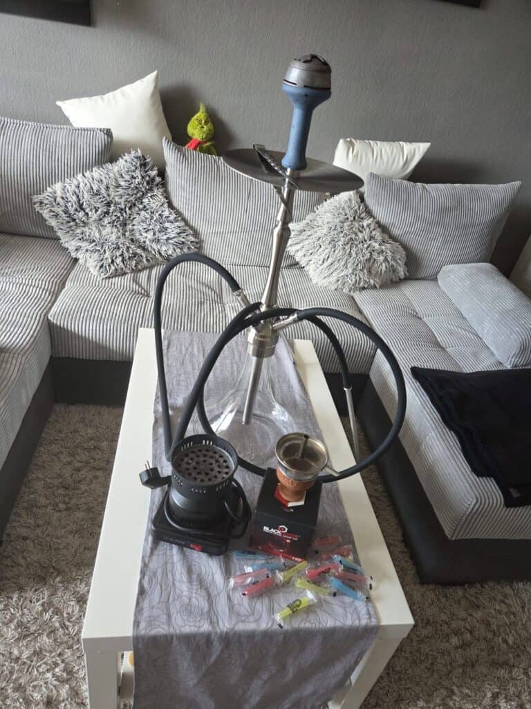 Shisha-Rauchsäule mit Zubehör auf Tisch, Wohnzimmer-Setup.
