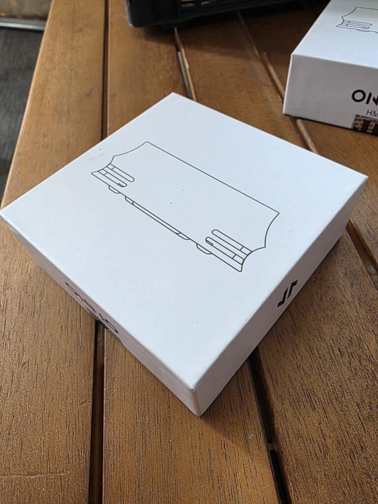 Weiße Verpackung mit einfachem Linien-Design, auf Holzoberfläche.