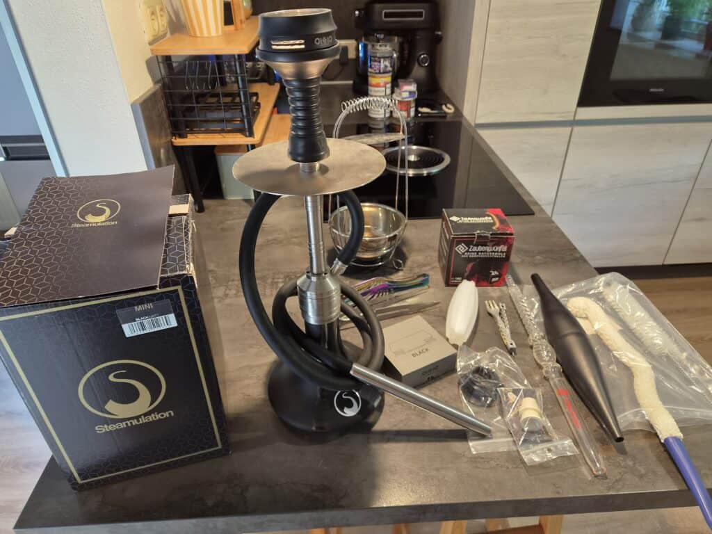 Shisha mit Silikonschlauch und Düse, komplett mit Zubehör, auf dunklem Tisch.