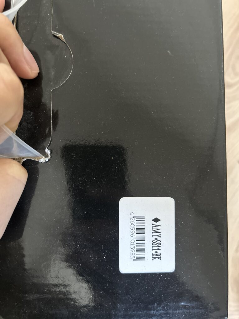 Schwarze Verpackung mit Barcode und Aufkleber, möglicherweise Produktetikett oder Versandmaterial.