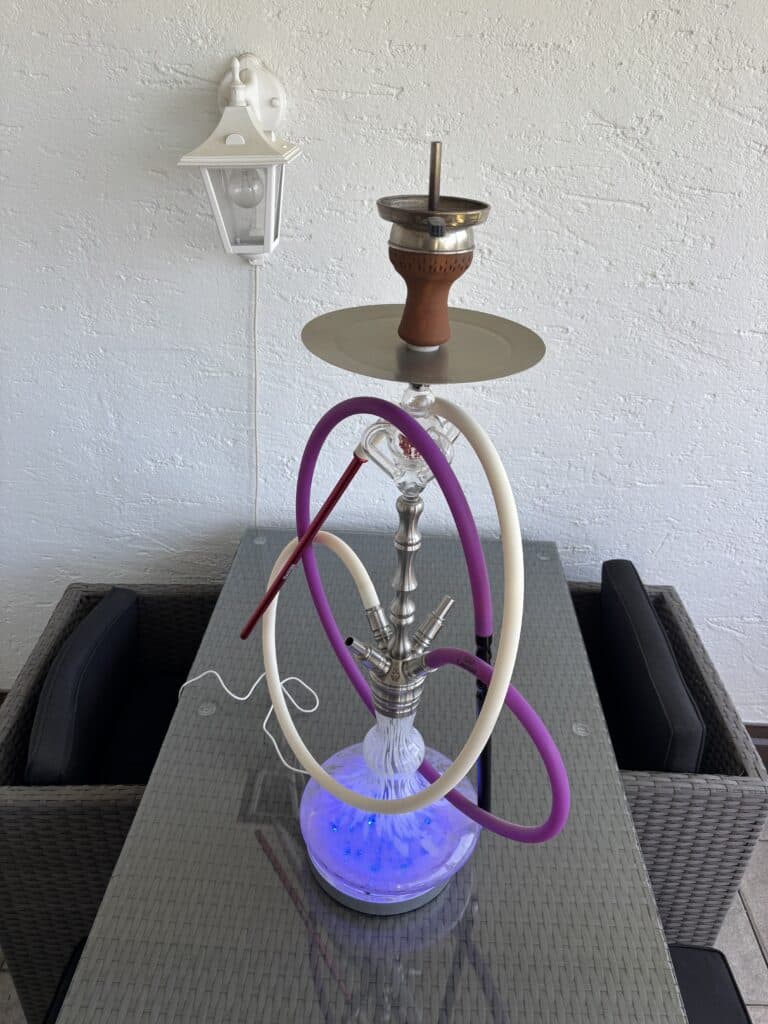 Rauchsäule mit Shisha, Wasserpfeife und Zubehör auf Tisch, moderne Dekoration.
