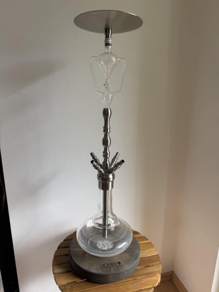 Shisha-Kopf mit Glasbowl und Metallhals auf Holzunterlage.