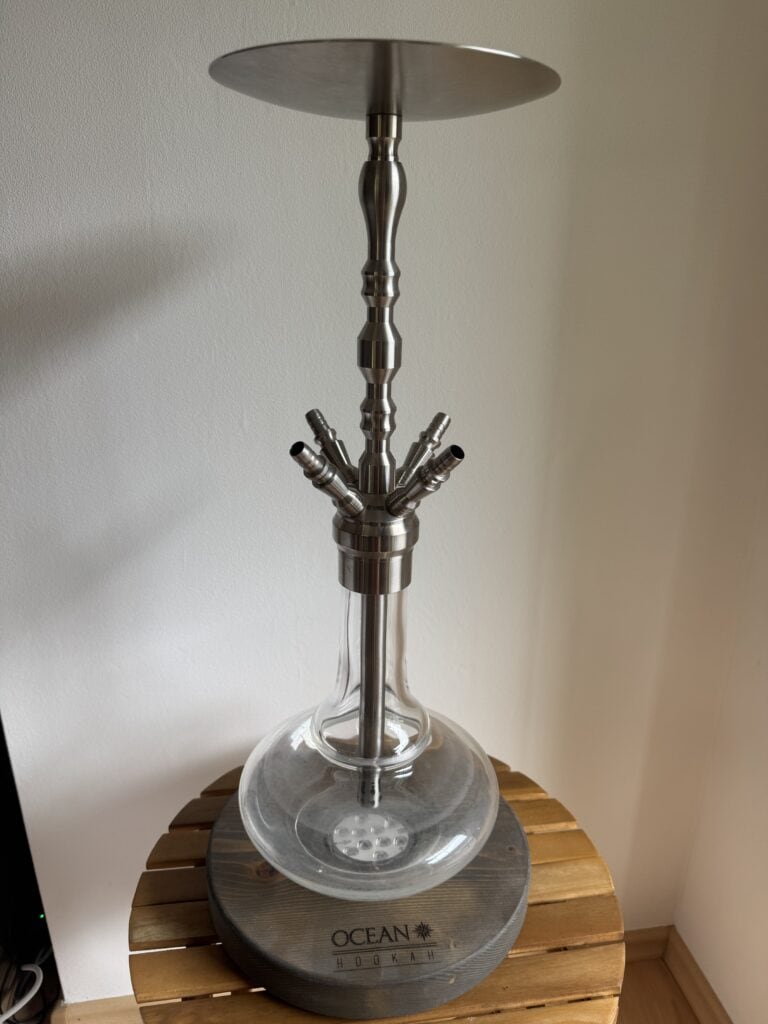 Shisha-Hookah mit Glasbowl und Metallstange auf Holztisch.