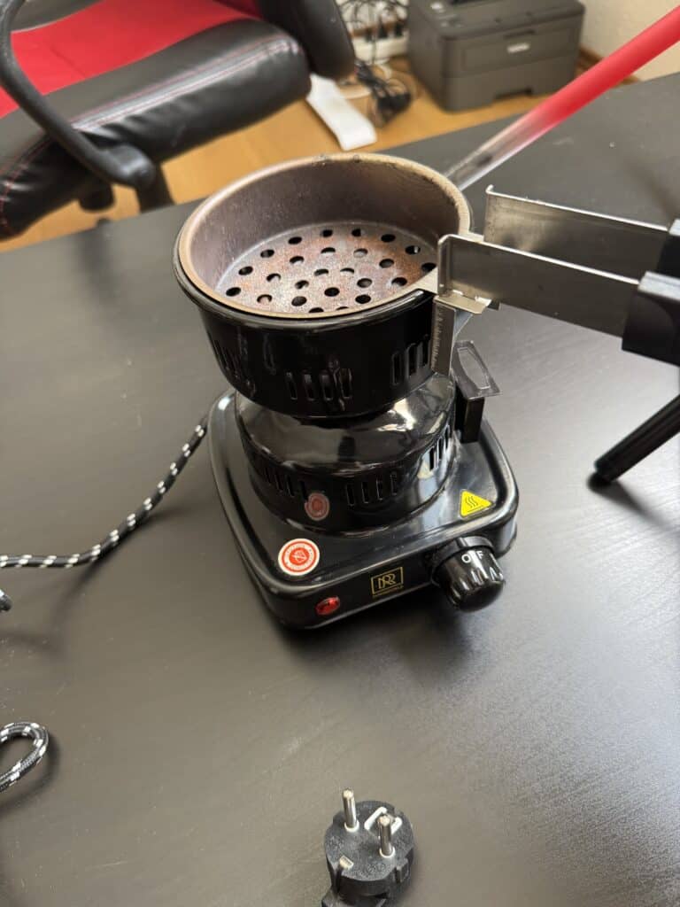Elektrischer Shisha-Ofen mit Metall- und Glasbowl, auf Tisch.