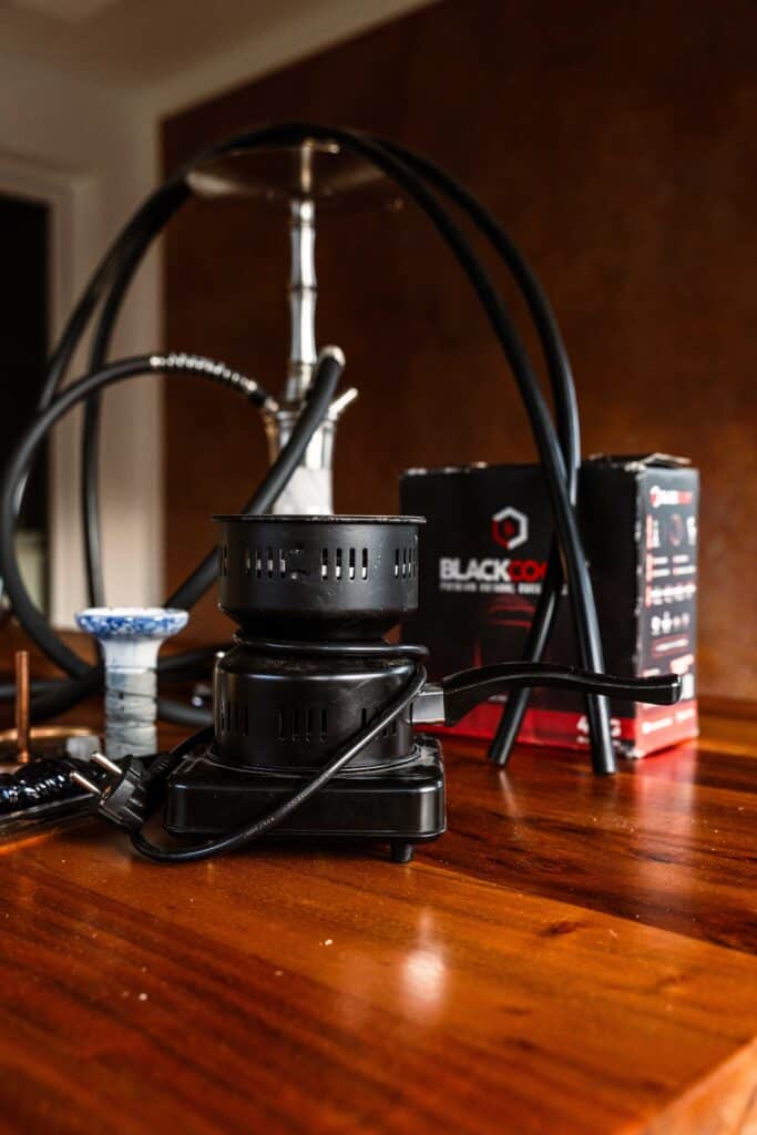 Elektrischer Shisha-Heizer auf Holzoberfläche mit Kabeln und Zubehör.