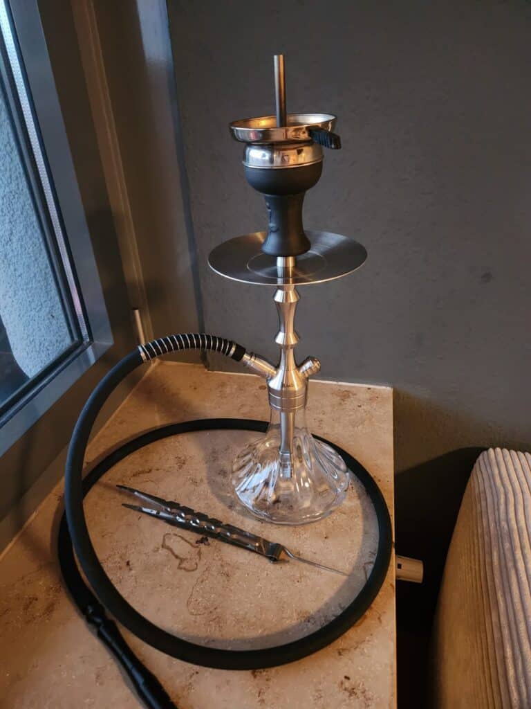 Schwarze Shisha mit Glasbowl und Metallaufsatz auf Tisch.
