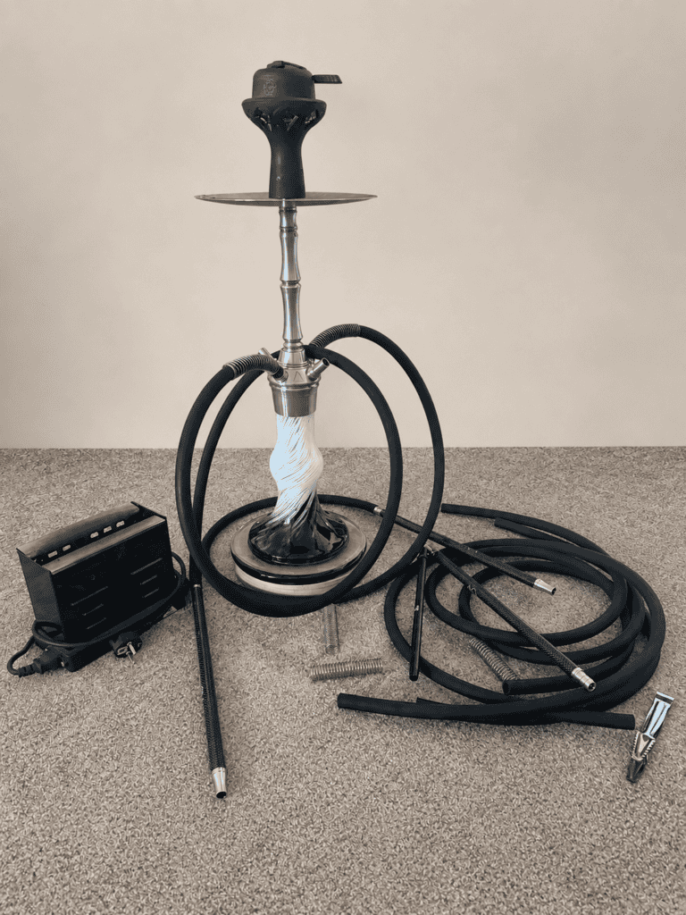 Shisha mit Glasbowl, Schlauch und Zubehör auf Boden.