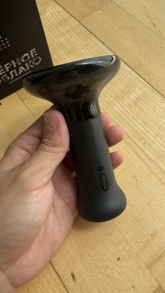 Schwarze Shisha Glasbowl in Hand gehalten auf Holztisch.