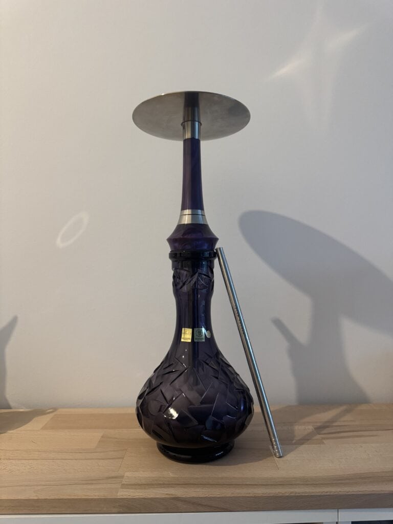 Schwarze Shisha mit Metallrohr und Glasbowl auf Holzplatte.