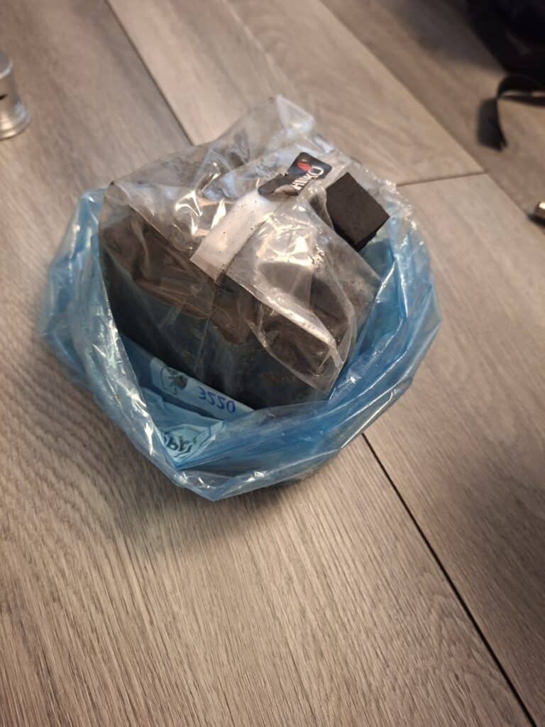 Verpacktes Shisha-Zubehör in blauer Tüte auf Holzboden.