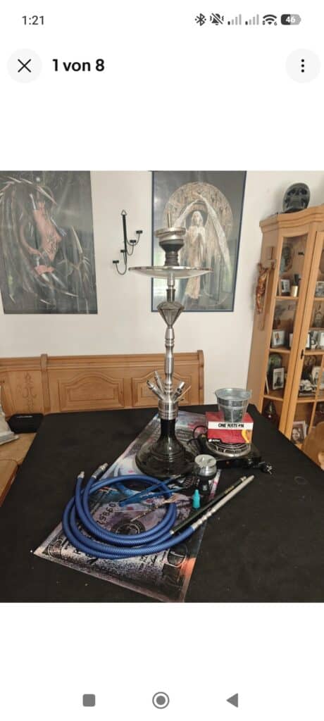 Shisha mit Glasbowl, Schlauch und Kohle auf Tisch.