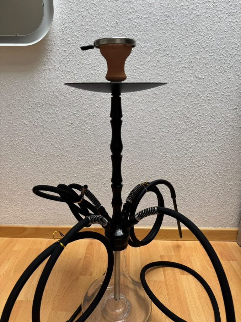 Shisha-Hookah mit Glasbowl und Schlauch auf Holzboden.