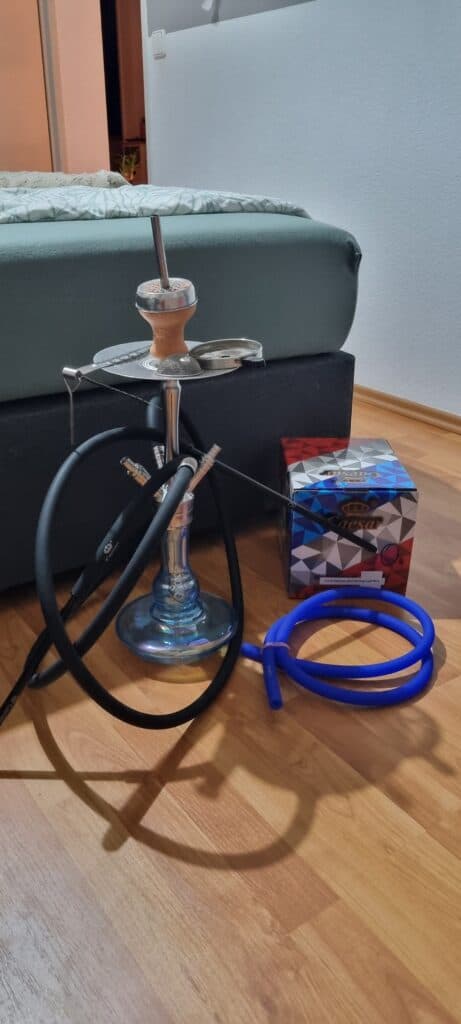 Verschiedene Shisha Teile, inklusive Glasbowl, Schlauch und Zubehör.