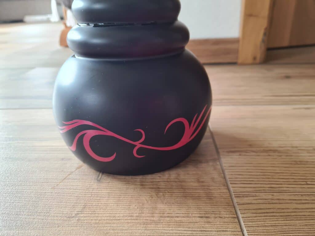 Schwarze Glasbowl für Shisha mit rotem Muster, auf Holztisch.