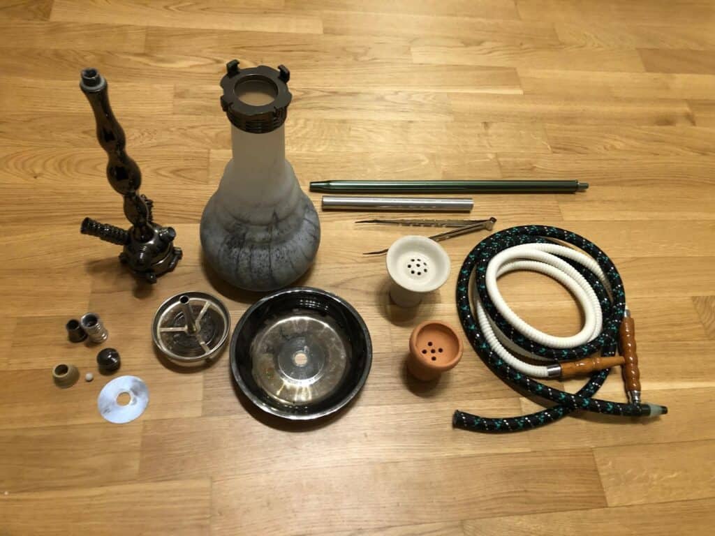 Verschiedene Shisha Teile, inklusive Glasbowl, Schlauch und Dichtungen.