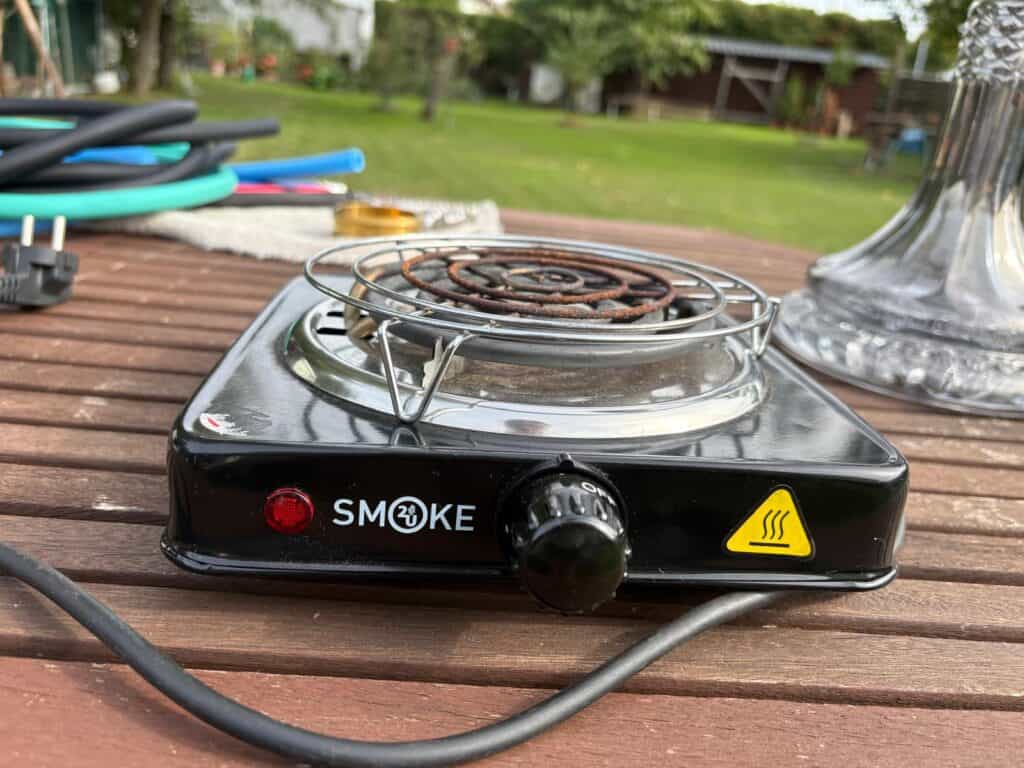 Kleiner elektrischer Heizofen auf Holzterrasse mit Kabel und Zubehör.