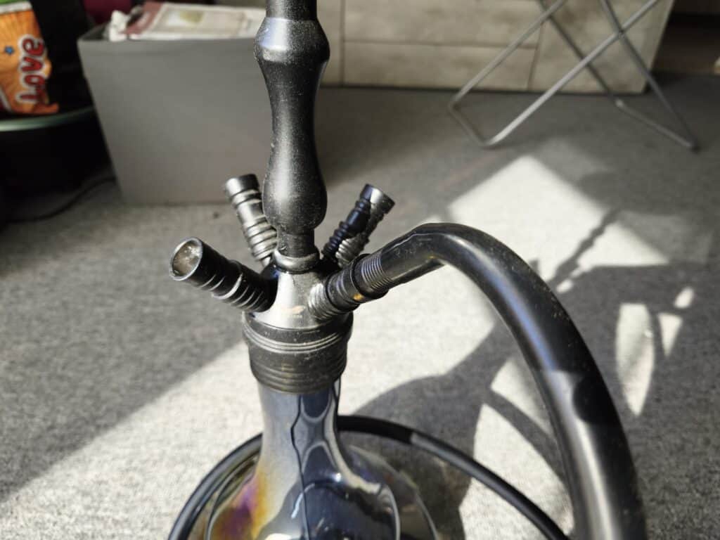 Schwarze Shisha mit Metall- und Glasbowl, auf Terrasse.
