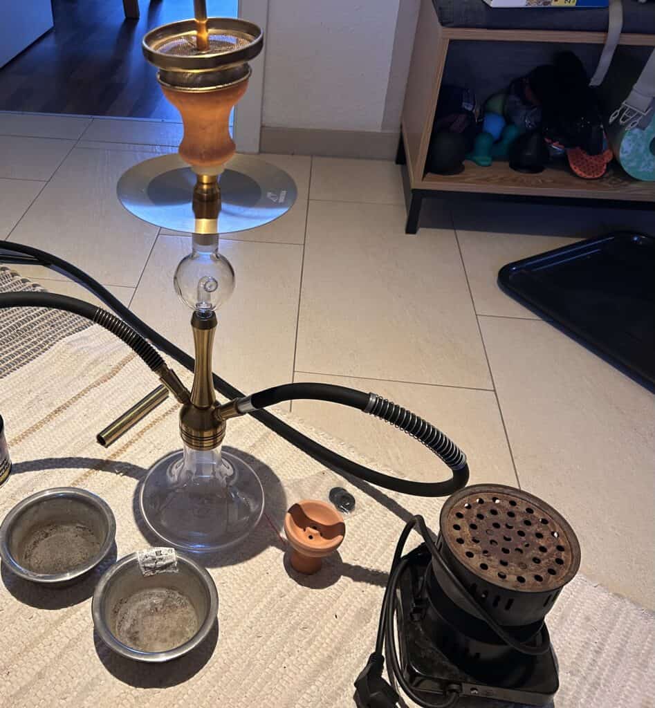 Shisha mit Glasbowl, Kohle und Zubehör im Raum.