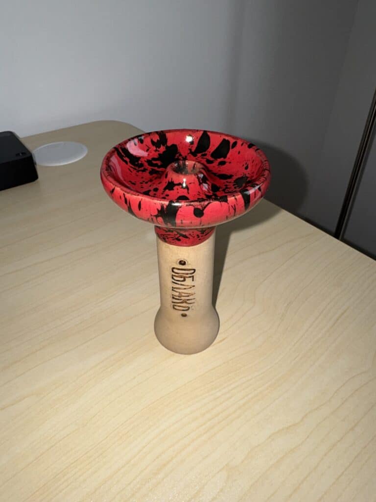 Shisha-Glasbowl mit rotem und schwarzem Muster auf Holzständer.
