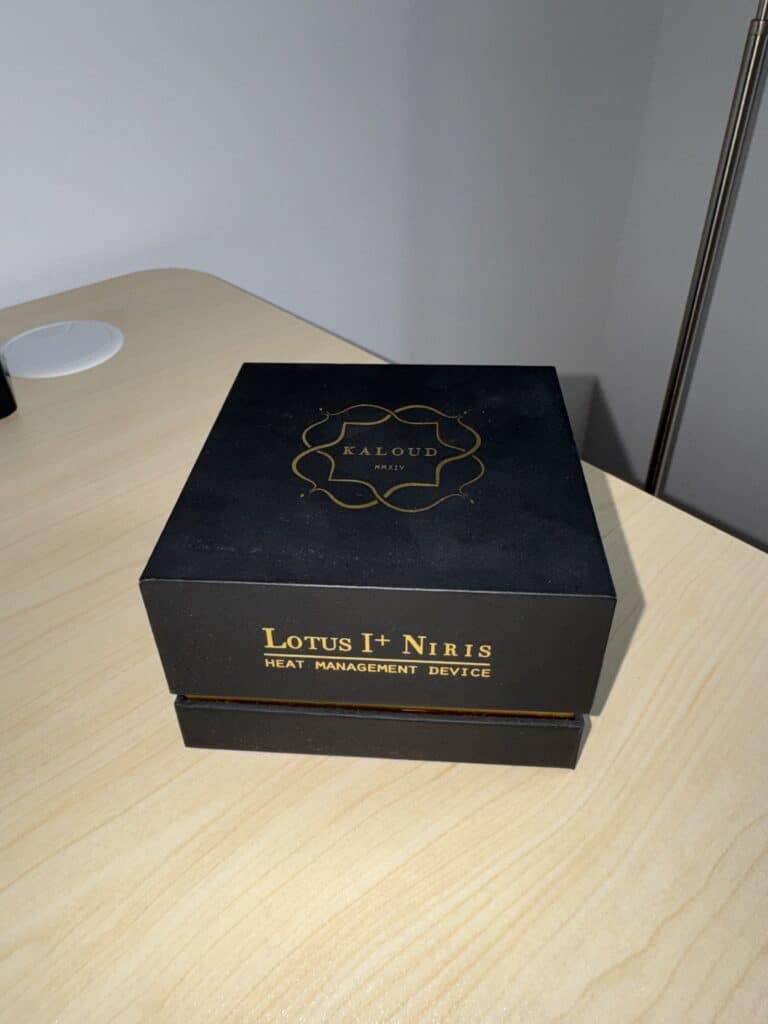 Schwarzes Lotus+ Niris Heizmanagement Gerät auf Holztisch.