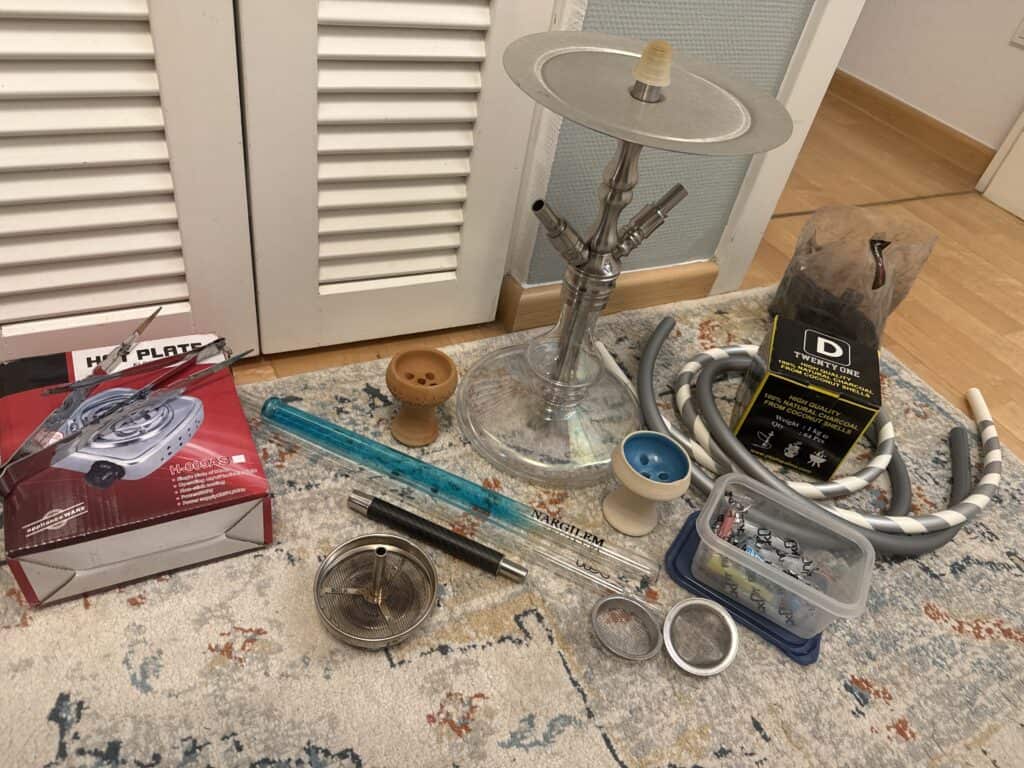 Verschiedene Shisha Teile und Glasbowl auf Teppichboden.