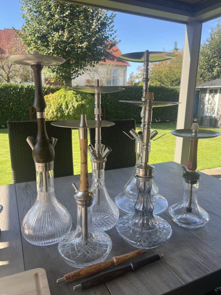 Mehrere Glasbowl-Modelle für Shisha auf Tisch im Garten.