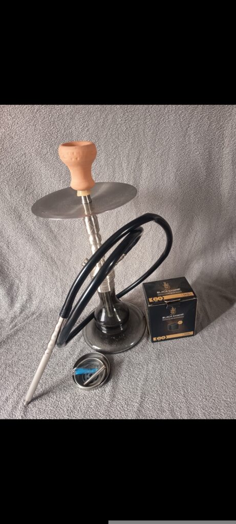 Shisha-Kopf mit Glasbowl, Schlauch und Zubehör auf Tisch.
