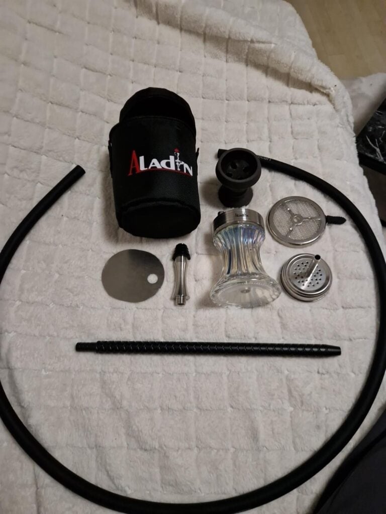 Verschiedene Shisha Ersatzteile und Glasbowl auf Bett.
