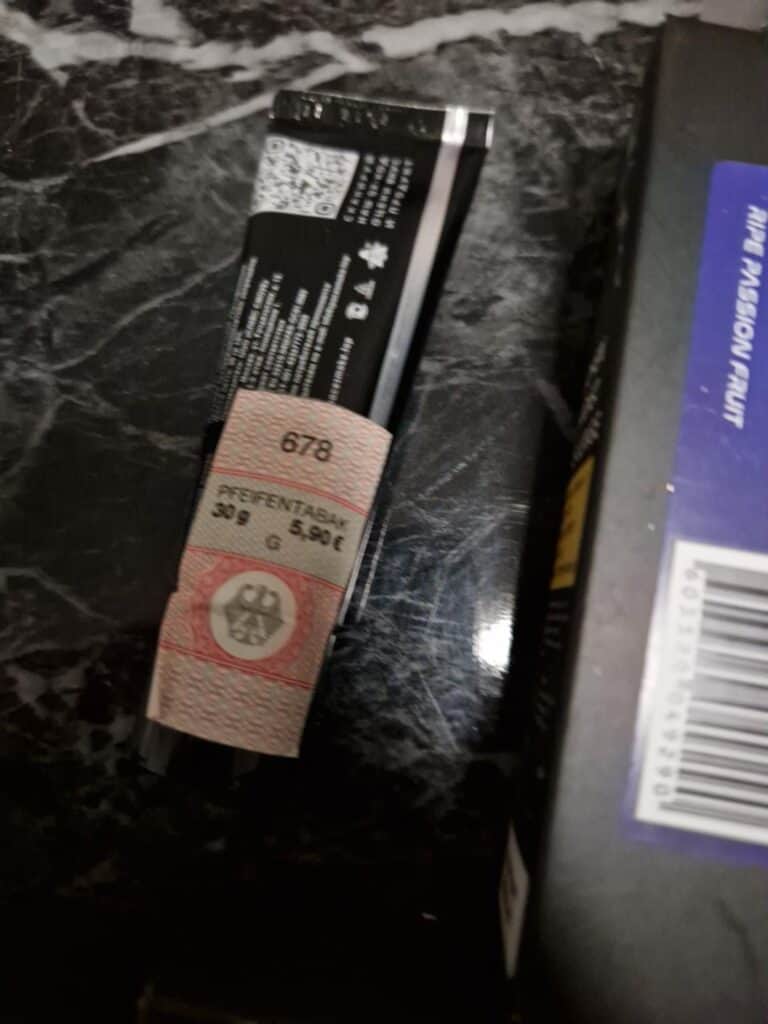 Verpackung eines Shisha-Zubehörartikels auf schwarzer Marmoroberfläche.