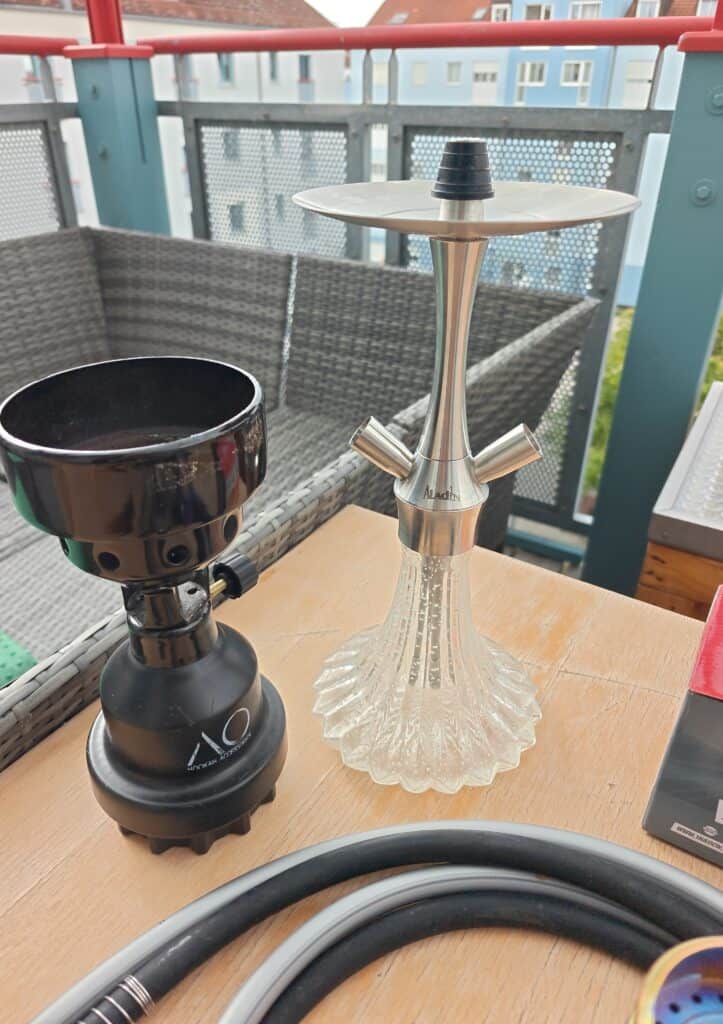 Shisha-Kohleanzünder und Glasbowl auf Balkon mit Sitzbereich.